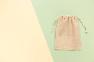 Asma ipli bez çanta, doğal pamuk kumaştan yapılmış küçük eko çuvalın maketi üst görünümden yeşil pastel arka planda yatıyordu.