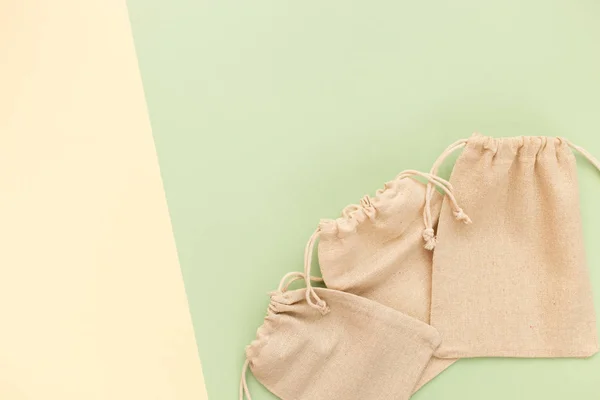 Bolsas de lona con cordón, maqueta de pequeño saco ecológico hecho de tela de algodón natural plana sobre fondo verde pastel desde la vista superior — Foto de Stock