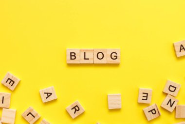 Sarı arka planda blog yazan tahta küplü harfler. Üst görünüm, düz görünüm, kopyalama alanı.