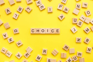 Tahta küp harfleri ve sarı arka planda kelime seçimi. Üst görünüm, düz görünüm, kopyalama alanı.