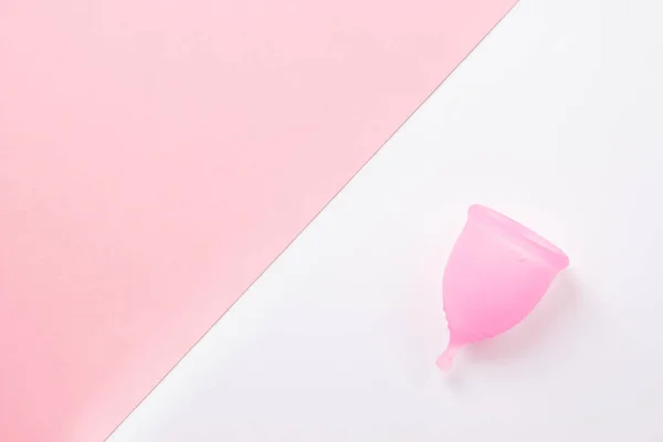 Cangkir menstruasi pink dengan latar belakang merah muda dan putih. Datar berbaring, pemandangan atas. menyalin ruang . — Stok Foto