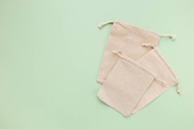 Canvas bags with drawstring, mockup of small eco sack made from natural cotton fabric cloth flat lay on green pastel background from top view clipart
