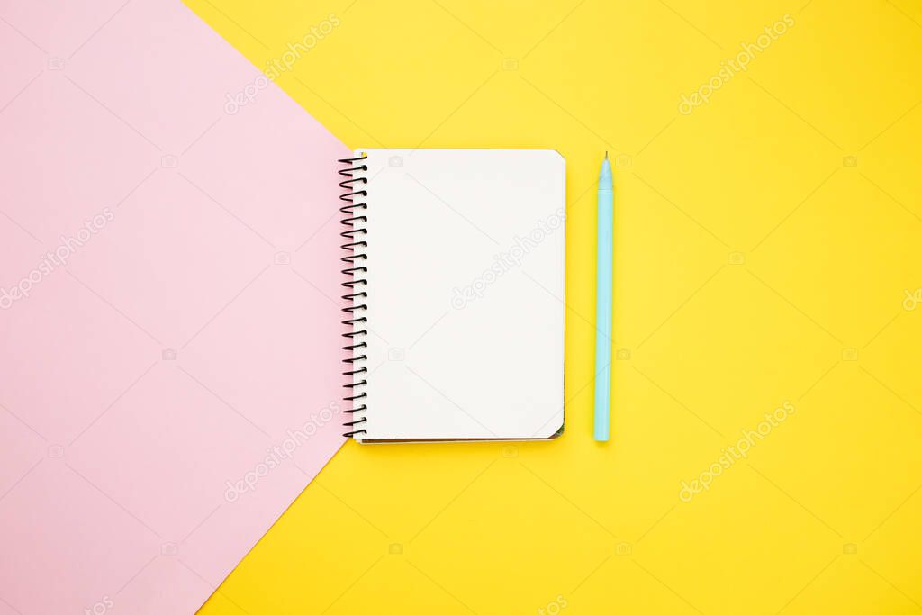 Notebook on art paper blue and yellow background. Flat lay, top view.