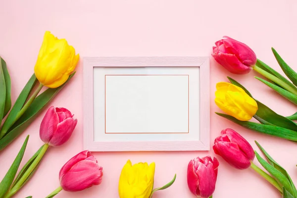 Happy Women\'s Day, Mother\'s Day greeting card concept. Pink tulips flowers and photo frame on pink background, copy space for your text. Top view, flat lay