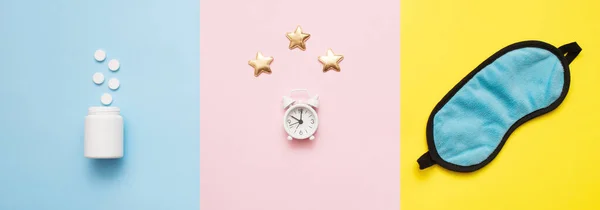 Haplar, şişe, uyku maskesi ve pembe, sarı, mavi sanat arka planında yıldızlar olan beyaz çalar saat. Insomnia kavramı, uyku sorunları, ilaç alıp tedavi olma zamanı. Üst görünüm, düz görünüm, kopyalama alanı.