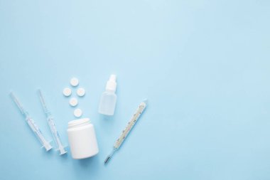 Haplar mavi arka planda şırınga termometresinden dökülüyor. Virüs koruma konsepti. Düz konum, üst görünüm, kopyalama alanı