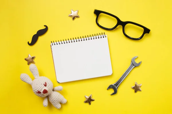 Vaderdag concept kaart met mans werktuig op gele achtergrond en geschenkdoos, snor, bril en notitieblok. Bovenaanzicht, flat lay, kopieerruimte. — Stockfoto