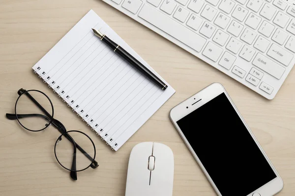 Bureau d'affaires moderne avec clavier, bloc-notes, téléphone intelligent, stylo, souris et lunettes. Vue supérieure avec espace de copie Image En Vente