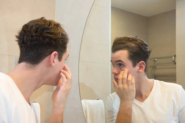Young caucasian man taking care of his face  looking at mirror r — 스톡 사진