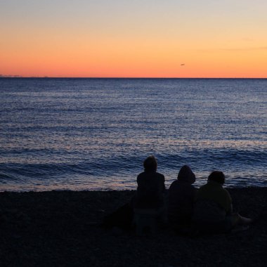 Yaz gün batımı saatinde Soçi'de Karadeniz kıyısında insanların silueti, Rusya Federasyonu. Seçilen Odak.