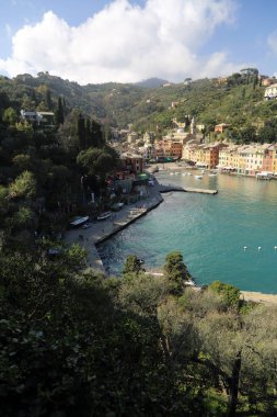 Portofino, İtalya - 5 Nisan 2018: Lüks İtalyan tatiller - güzel Portofino Ligurian kıyısında. Mavi su ve misafir Portofino, köy taç aracılığıyla koy görünümü.