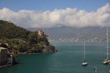 Portofino, İtalya - 5 Nisan 2018: Lüks İtalyan tatiller - güzel Portofino Ligurian kıyısında. Mavi su ve misafir Portofino, köy taç aracılığıyla koy görünümü.