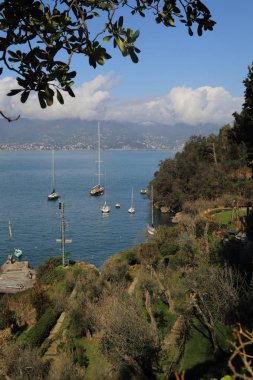 Portofino, İtalya - 5 Nisan 2018: Lüks İtalyan tatiller - güzel Portofino Ligurian kıyısında. Mavi su ve misafir Portofino, köy taç aracılığıyla koy görünümü.