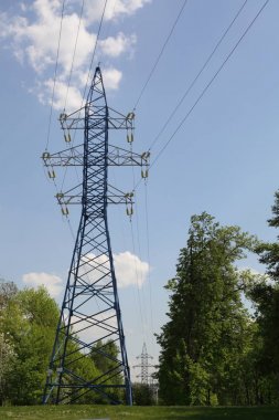 Yüksek gerilim elektrik iletim hattı dış görüntü mavi bulutlu gökyüzünde metal inşaat kulesi pillon destek. Metal elektrik direci. Endüstriyel arka plan. Güç iletim kulesi endüstrisi.