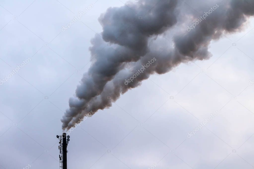 Thick clouds of smoke billowing out of an industrial chimney 