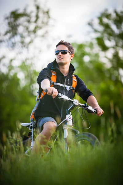 Красивий молодий чоловік їде на велосипеді в сільській місцевості — стокове фото