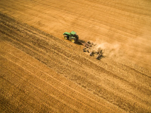 Vista aérea de um trator que trabalha num campo após a colheita — Fotografia de Stock