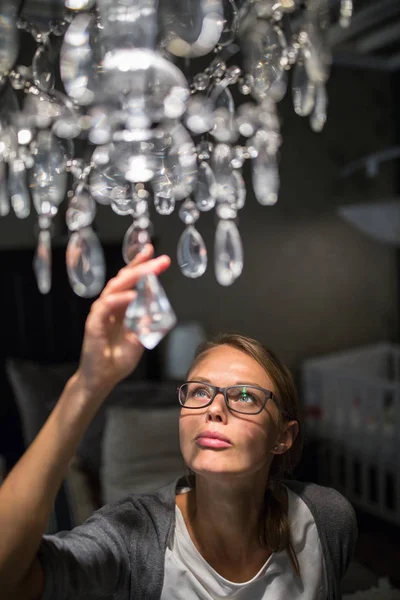 Vacker, ung kvinna att välja rätt ljuskrona för hennes lägenhet — Stockfoto