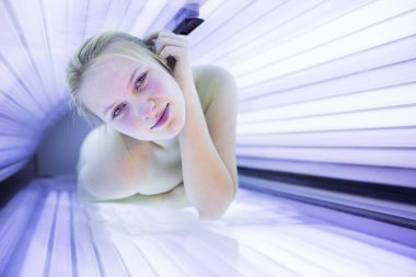 Pretty, young woman tanning her skin in a modern solarium (shall clipart