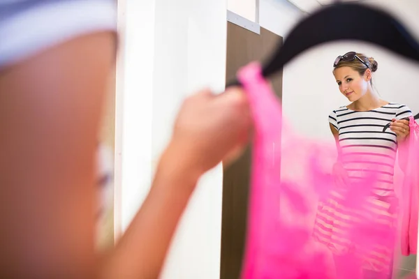 Молодая женщина делает покупки в магазине моды, примеряет одежду — стоковое фото