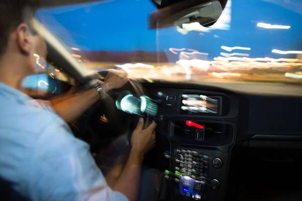Driving a car at night - young man driving his modern car — Stock Photo, Image