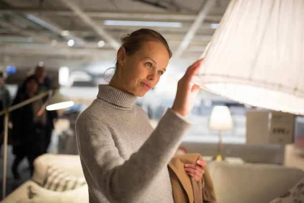 Jolie, jeune femme choisissant la bonne lampe pour son appartement — Photo