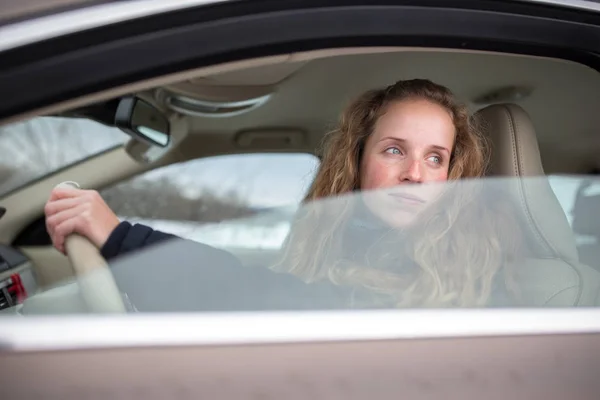 Hübsche junge Frau am Steuer ihres neuen Autos (flach dof; Farbe getönt — Stockfoto