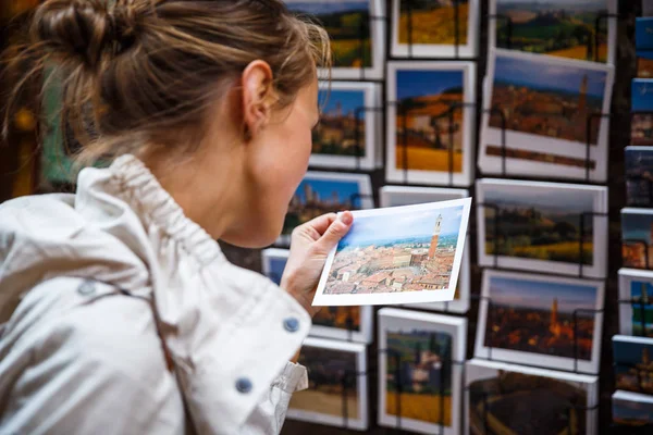 Jonge vrouw die het kiezen van de juiste briefkaart home verzenden vanuit een vaca — Stockfoto
