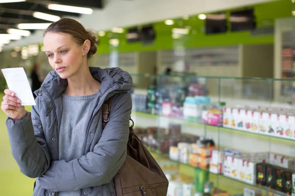 Mujer joven que busca las píldoras adecuadas en una farmacia moderna — Foto de Stock