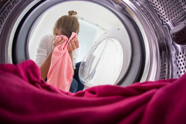 Young woman doing laundry - view from the washing machine clipart