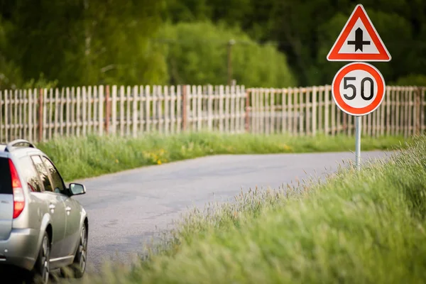 Car on a country road with limited speed and crossroad sign — Stock Photo, Image