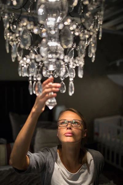 Mujer joven y bonita eligiendo la lámpara de araña adecuada para su apartamento —  Fotos de Stock