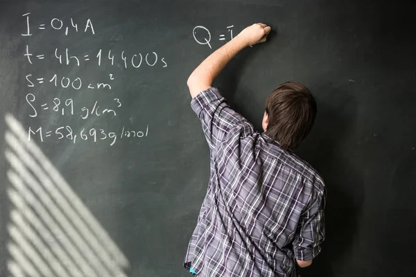 College student solving a math problem during math class in front of the blackboard/chalkboard — Stock Photo, Image