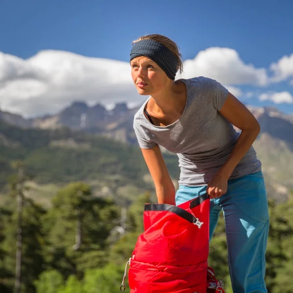 Vacker, kvinnlig vandrare i höga berg packar sin ryggsäck — Stockfoto