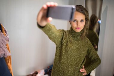 Genç kadın bir moda mağazasında alışveriş üzerine bir şeyler çalışıyor 