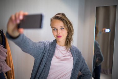 Genç kadın bir moda mağazasında alışveriş üzerine bir şeyler çalışıyor 