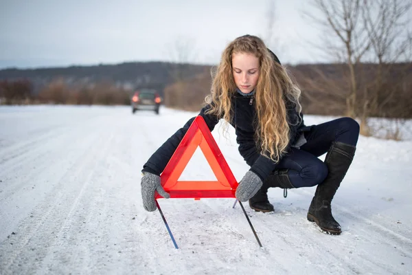 Ung kvinna att inrätta en varningstriangel och efterlyser hjälp — Stockfoto