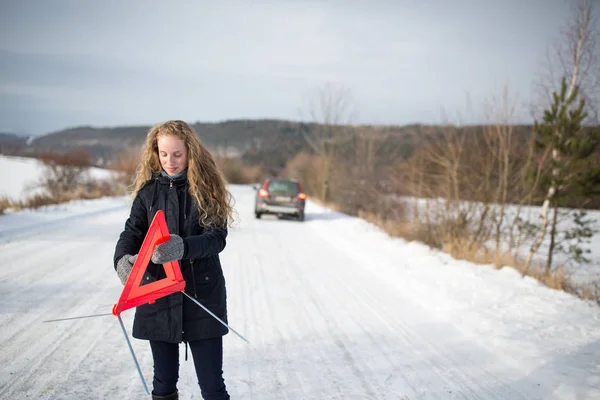 Молодая женщина устанавливает предупреждающий треугольник и зовет на помощь — стоковое фото