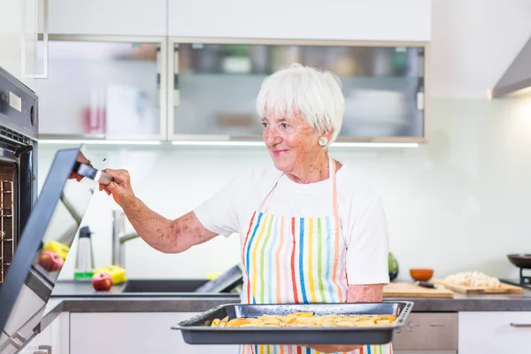 Seniorin kocht in der Küche - gesund essen und kochen — Stockfoto
