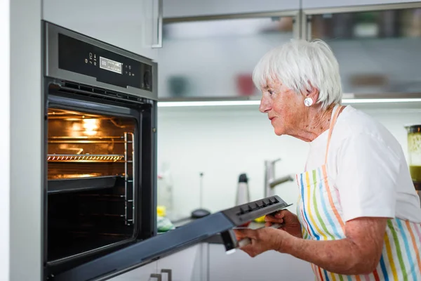 Пожилая женщина готовит на кухне - есть и готовить здоровую пищу — стоковое фото