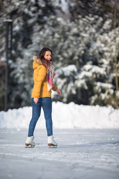 Jovem mulher patinação no gelo ao ar livre em uma lagoa em um inverno gelado — Fotografia de Stock