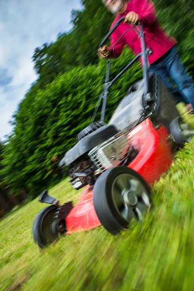 Homem sênior cortando o gramado em seu jardim — Fotografia de Stock