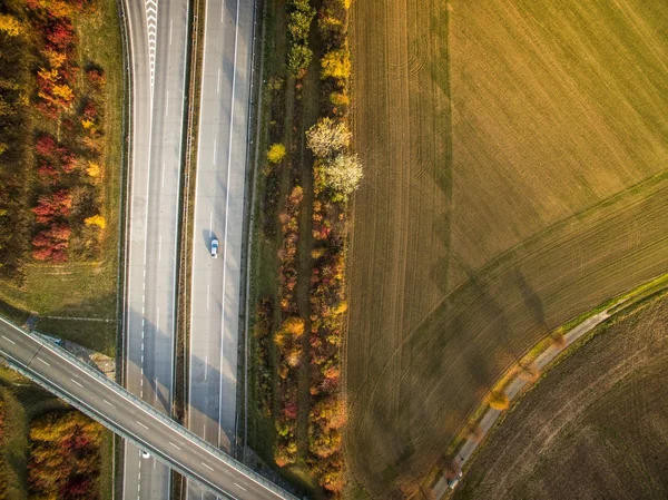 Vista aérea de una carretera en medio de campos con coches en ella —  Fotos de Stock