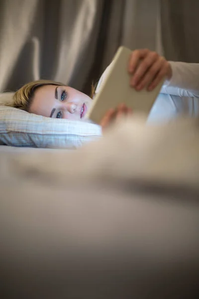 Νεαρή γυναίκα χρησιμοποιώντας τον υπολογιστή tablet στο κρεβάτι της, αργά τη νύχτα — Φωτογραφία Αρχείου
