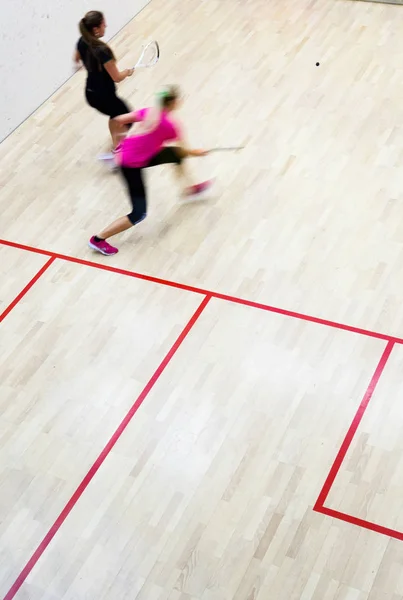 Twee vrouwelijke squash spelers in snelle actie op een squashbaan — Stockfoto