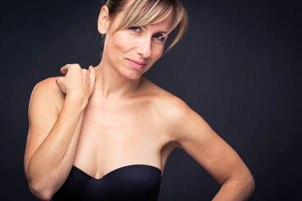 Retrato de uma mulher branca de meia-idade sorridente contra fundo escuro — Fotografia de Stock