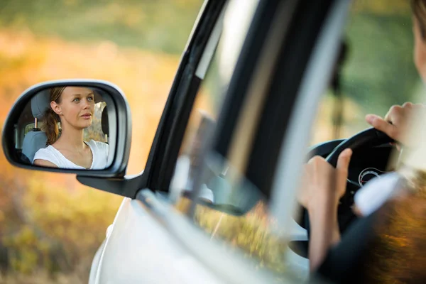 Mulher bonita, jovem dirigindo seu carro - reflexão no espelho lateral — Fotografia de Stock