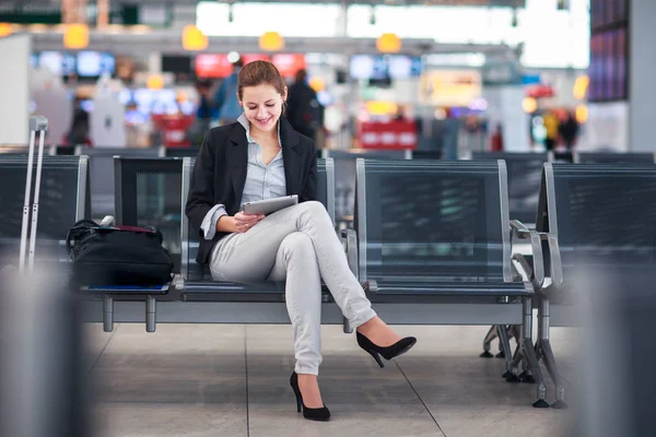 Jonge vrouwelijke passagier op de luchthaven, met behulp van haar tablet-pc — Stockfoto