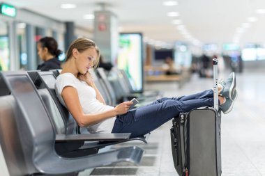 genç bir kadın yolcu havaalanında, tablet bilgisayarını kullanarak