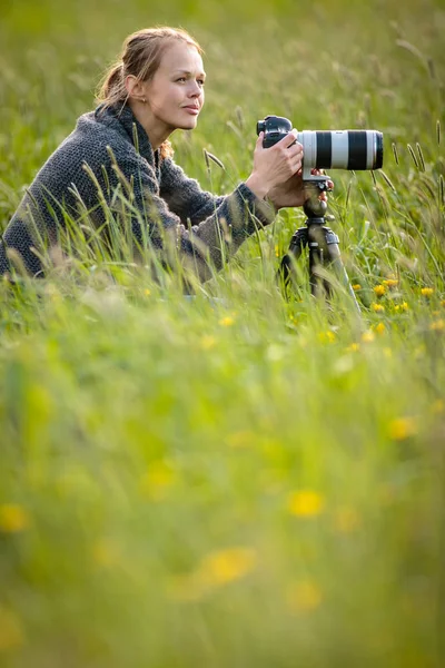 Bella giovane donna con una fotocamera DSLR all'aperto, utilizzando un treppiede , — Foto Stock